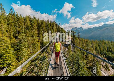 Donna escursioni in montagna attraversando ponte sospeso piedi con vista mozzafiato. Canada Turismo concetto dalla Columbia Britannica. Escursionista turista in Foto Stock