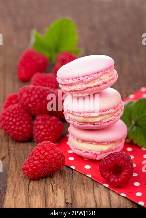 Biscotti rosa al macaron di lamponi su tavole di legno scuro Foto Stock