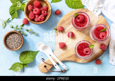 Colazione sana. Budino di semi di Chia con lampone e marmellata o frullati con semi di chia su un tavolo di pietra. Vista dall'alto. Foto Stock