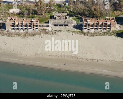 VISTA AEREA. Abbandonati alloggi su più piani su una spiaggia nella città di Vlorë. Contea di Vlorë, Albania. Foto Stock