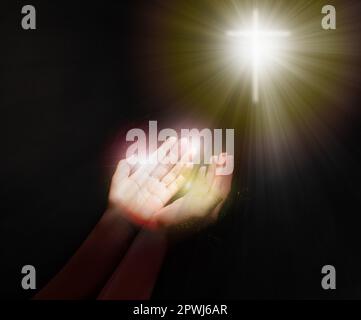 Donna che allunga le mani verso la silhouette trasversale nel buio, primo piano. Concetto di preghiera Foto Stock