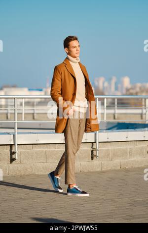 Abbigliamento primavera - autunno. Street fashion. Giovane uomo in pantaloni a scacchi, maglione e cappotto di lana. Foto Stock