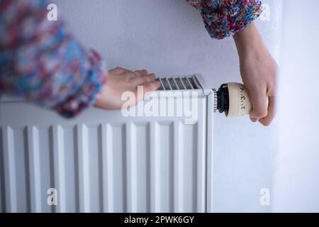 Donna fredda, depressa di mezza età a casa sentirsi triste, solitario, ansioso per i prezzi dell'energia in aumento (immagine dai toni del colore) Foto Stock