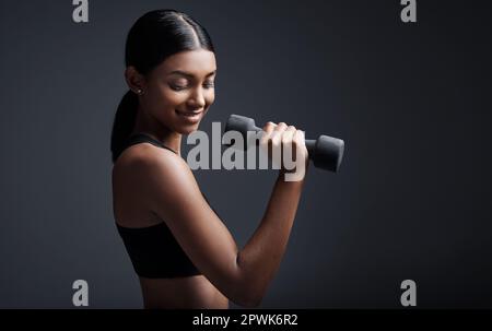 La fiducia in se stessi è il muscolo più forte che si può possedere. Studio shot di un giovane sportivo che fa esercizi di manubri su uno sfondo grigio Foto Stock