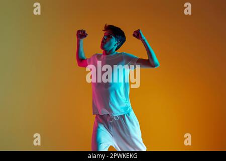 bel ragazzo che balla su sfondo giallo. Illuminazione al neon Foto Stock