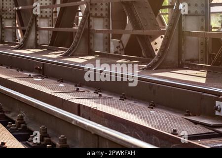 Ponte ferroviario, dettaglio sulle vie, piastre di acciaio grandi dadi e bulloni illuminato da sun. Foto Stock