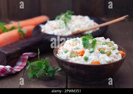 Ciotola di insalata russa olivier con carne e verdure su un tavolo di legno. Cibo popolare per Capodanno e Natale. Foto Stock