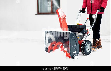 Spazzaneve alimentato a benzina in azione. Uomo all'aperto di fronte a casa con una fresa da neve. Rimozione neve, aiuto lanciatore in inverno fuori h Foto Stock