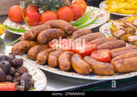 Street food in Ucraina - frankfurters alla griglia sdraiato sul piatto con pomodori e funghi primo piano Foto Stock