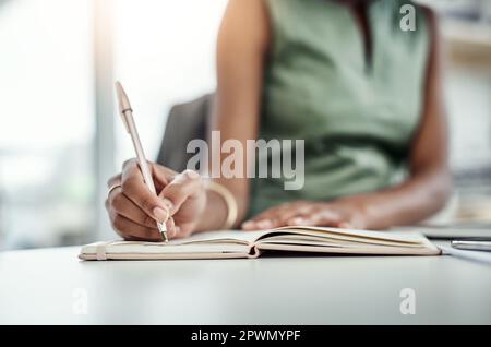 Diarizing eventi importanti. una giovane donna d'affari irriconoscibile che scrive nel suo diario mentre lavora in ufficio Foto Stock