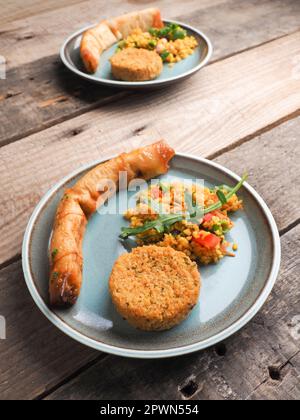 Gustoso Falafel con bulgur piccante e un rotolo di pasta vegetariano su un piatto di ceramica, tradizionale cibo caldo Foto Stock