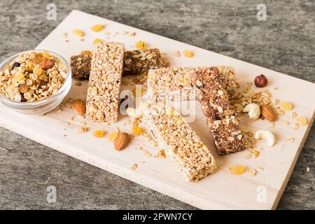 Vari barrette di muesli su sfondo tavolo. Barrette di cereali. Bar per la colazione superfood con avena, noci e frutti di bosco, primo piano. Concetto superfood. Foto Stock