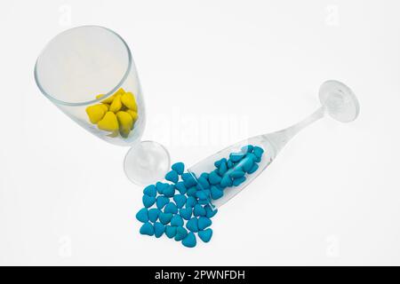Vetro con vetro giallo e rovesciato con dolci blu a forma di cuore (primo piano) isolato su fondo bianco. Simboli di Stato dell'Ucraina Foto Stock