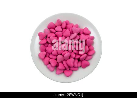 Piatto bianco con caramelle rosa a forma di cuore (primo piano) isolato su sfondo bianco. Vista dall'alto Foto Stock