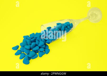 Vetro rovesciato con caramelle a forma di cuore blu (primo piano) isolate su sfondo giallo. Simboli di Stato dell'Ucraina. Vista dall'alto Foto Stock
