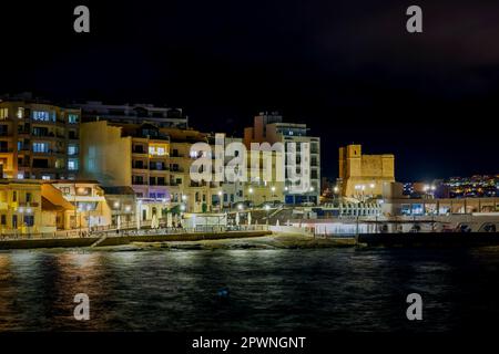 Malta, St Paul's Bay: Vista panoramica notturna della St Paul's Bay, una popolare destinazione turistica nella parte nord-occidentale di Malta. Foto Stock