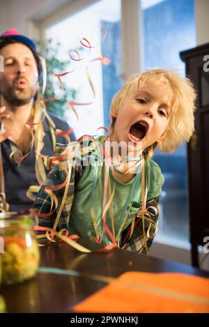 Padre e figlio festeggiano una festa con gli streamer di carta Foto Stock
