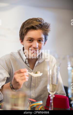 Ragazzo adolescente che mangia cibo alla festa di compleanno Foto Stock