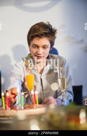 Ragazzo adolescente che accende le candele sulla torta Foto Stock