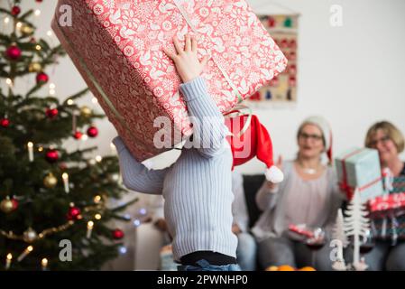 Bambino che trasporta la scatola grande di cartone durante Natale Foto Stock