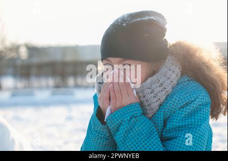 La ragazza starnutisce in inverno Foto Stock