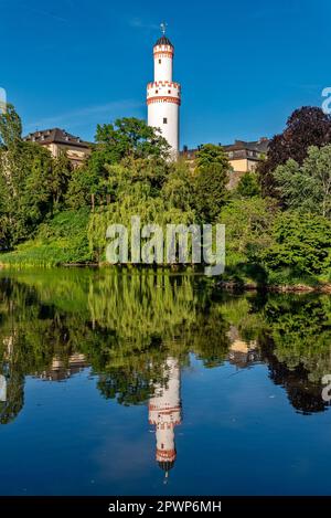 La torre bianca del castello di Bad Homburg vor der Höhe si riflette sulla superficie liscia dell'adiacente stagno del castello sotto un blu, senza nuvole Foto Stock