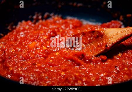 Mescolando con un cucchiaio di salsa di pizza di pomodoro. Foto Stock