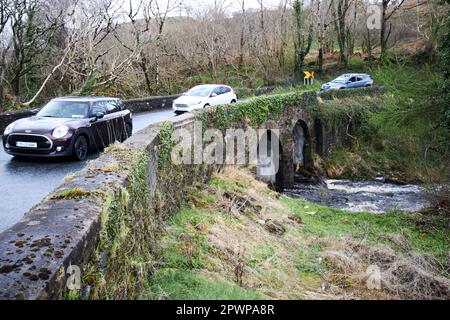 automobili che guidano sopra un ponte stretto sulla strada atlantica selvaggia con il fiume nella contea di inondazione donegal repubblica d'irlanda Foto Stock