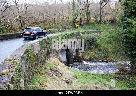 auto che guida su uno stretto ponte sulla selvaggia strada atlantica con il fiume nella contea di inondazione donegal repubblica d'irlanda Foto Stock