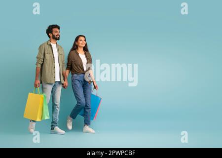 Spensierato gli amanti orientali che trasportano le borse di shopping, lo spazio della copia Foto Stock