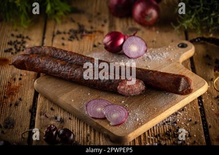 Salsiccia servita con cipolle su un tavolo di legno. Prodotto di coltivatore Foto Stock