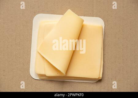 Fette di formaggio duro giacciono su un primo piano di cartone marrone, cibo Foto Stock
