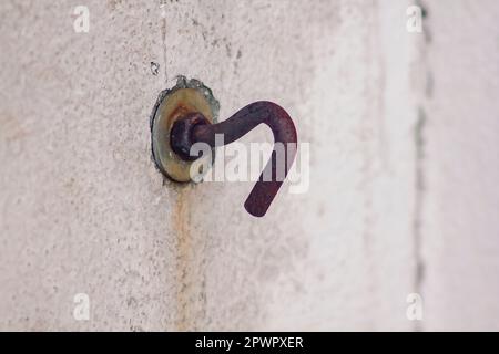 Vecchi ganci arrugginiti su pareti bianche. Foto Stock