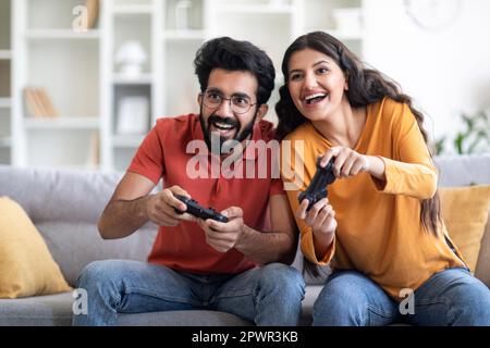 Coppia indiana allegra divertirsi a casa, giocare insieme ai videogiochi Foto Stock