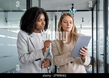 Due donne d'affari che lavorano insieme utilizzando un tablet pc digitale in un ufficio moderno. Foto Stock