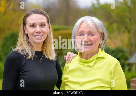Famiglia di due generazioni, madre e figlia, la figlia ha la mano sulla spalla della madre guardando amichevole la fotocamera Foto Stock