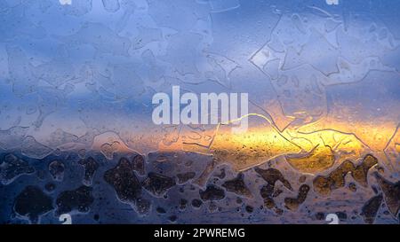 motivo gelido sul vetro. sfondo astratto della finestra ghiacciata. giorno d'inverno, il sole splende attraverso il vetro smerigliato sulla finestra Foto Stock