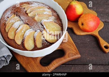 Brownie al cioccolato con una pera in un piatto da forno. Stile di raccolta del cibo. Sfondo autunno. Ingredienti per la sua preparazione . Foto Stock