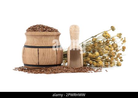 Semi di lino in barile di legno vicino a mazzo di piante di lino e paletta di legno isolata su fondo bianco Foto Stock