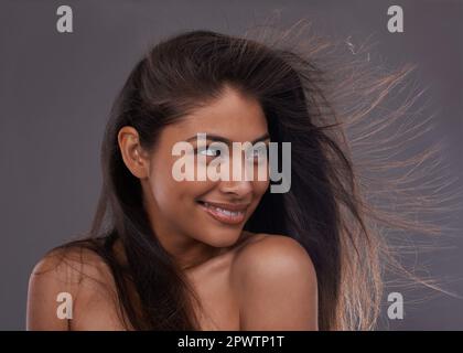 Shes sensazione di luminosità e brezza. una giovane donna attraente con i capelli spazzati dal vento in studio. Foto Stock