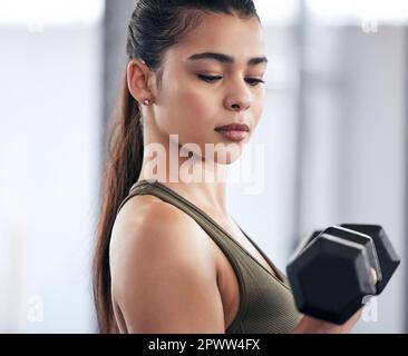 Mente sulla materia. una giovane donna che si allenava con pesi a manubri in palestra Foto Stock