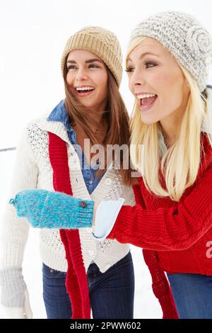 Andiamo a costruire un pupazzo di neve. due amici che hanno una risata fuori nella neve insieme. Foto Stock