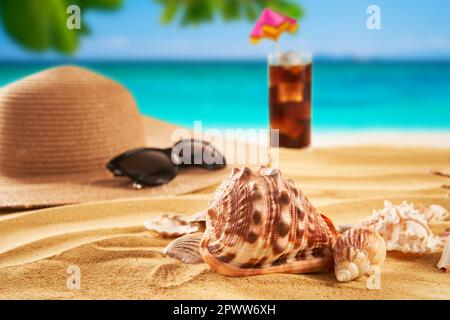Vacanza estiva concetto. Cappello di paglia, conchiglie sulla spiaggia di sabbia e sullo sfondo del mare. Viaggi Foto Stock