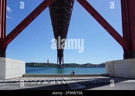 Vista dal basso del ponte sospeso del 25 aprile sul Tago. Collega il quartiere di Lisbona di Alcantara e la città di Almada, Lisbona, Portogallo Foto Stock