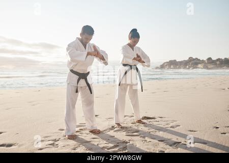 Un combattente deve avere onore. Foto a tutta lunghezza di due giovani artisti marziali che praticano il karate sulla spiaggia Foto Stock