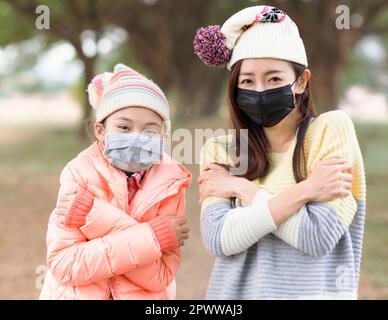 Madre e figlia che indossano la maschera medica di protezione del viso Foto Stock