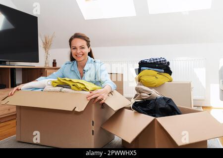 Giovane donna che indossa i propri abiti per inviare a organizzazioni caritative. Foto Stock