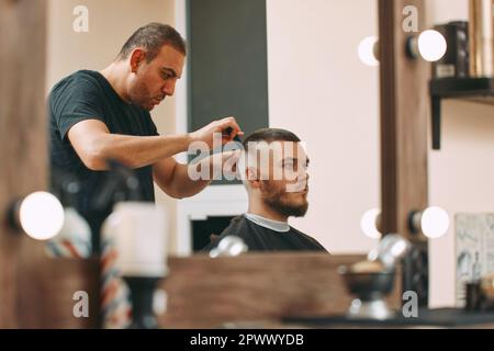bell'uomo che visita l'hairstylist nel barbiere Foto Stock