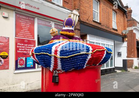 Cassetta postale rossa decorata con corona di incoronazione a maglia e ORB, maggio 2023, per l'incoronazione di Re Carlo III, Farnborough, Hampshire, Regno Unito Foto Stock