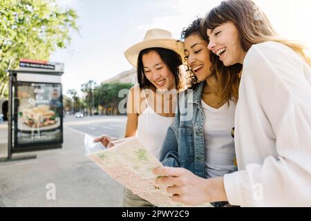Tre belle donne giovani adulti che guardano la mappa della città mentre visitano la città Foto Stock